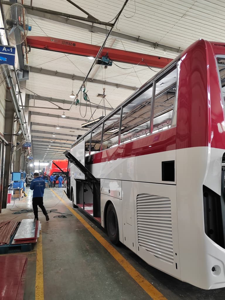 Coach on assembly line with luggage bay open under overhead crane